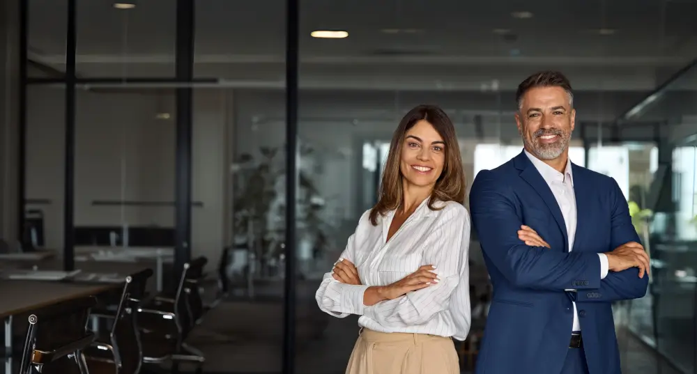 Business professionals standing confidently in office.
