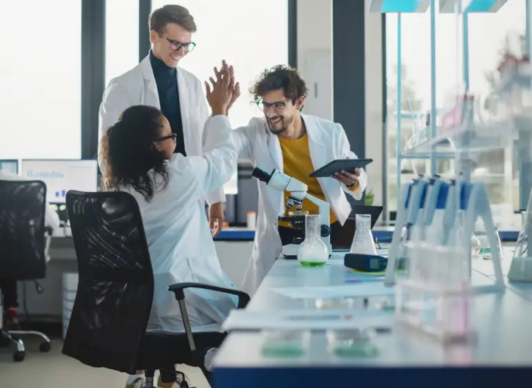 Scientists celebrating in a modern laboratory setting.