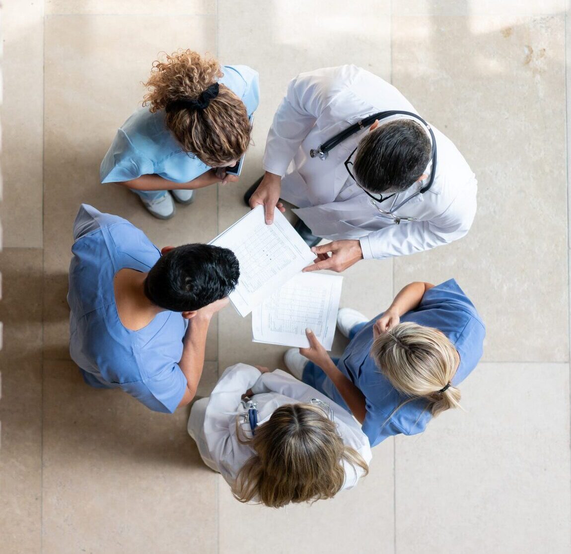 Healthcare professionals collaborating over patient charts in a circle.