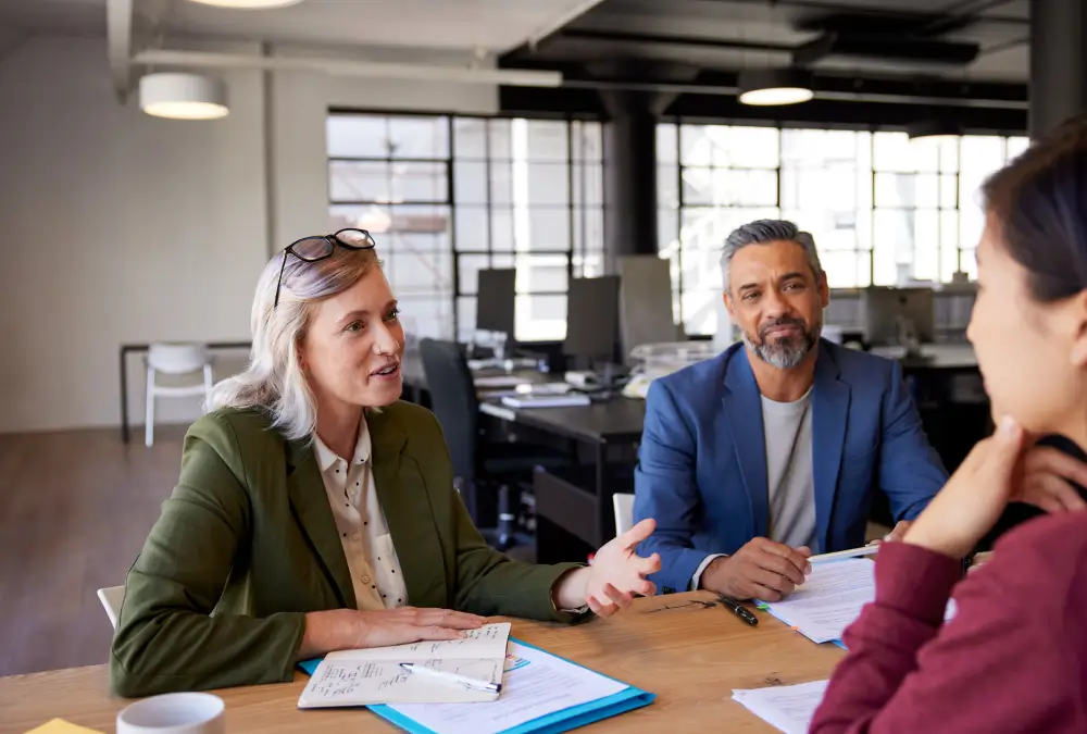 Office meeting with three people discussing.